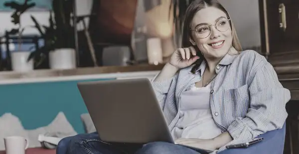 Eine junge Frau informiert sich an ihrem Laptop über das Wirtschaftspsychologiestudium.