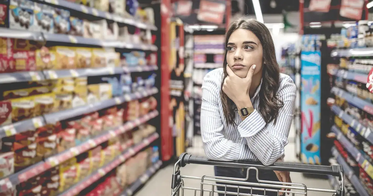 Eine Studierende der Angewandten Psychologie streift durch den Supermarkt und schaut sich die Produkte in den Regalen an.