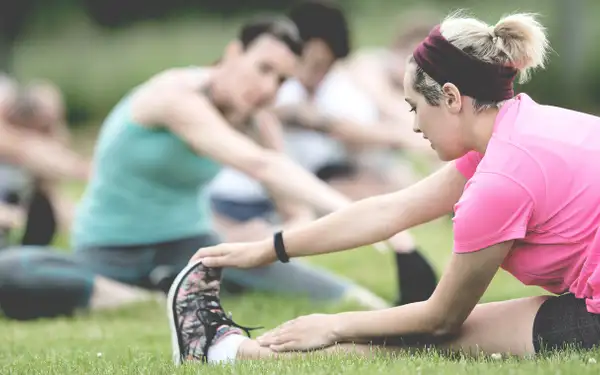Sportstudierende machen Yoga auf einer Wiese.