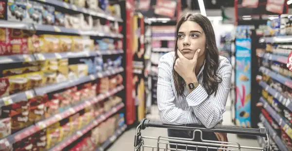 Eine Studierende der Angewandten Psychologie streift durch den Supermarkt und schaut sich die Produkte in den Regalen an.