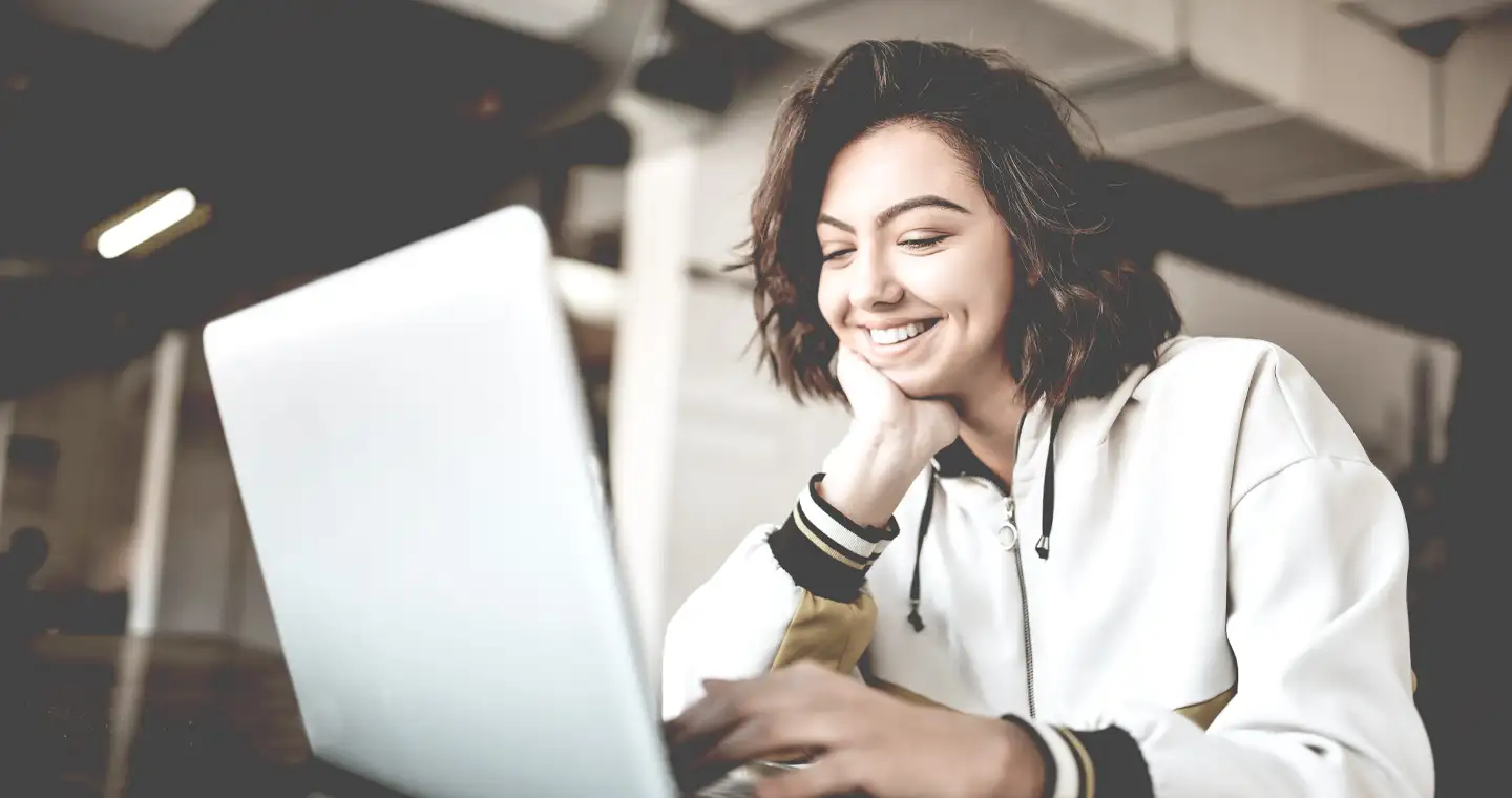 Studentin sitzt am Laptop und lächelt