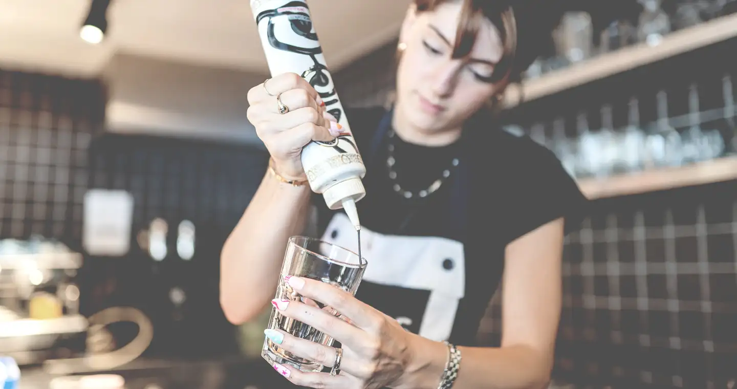 Studentin dekoriert ein Glas bei ihrem Nebenjob in einem Café.