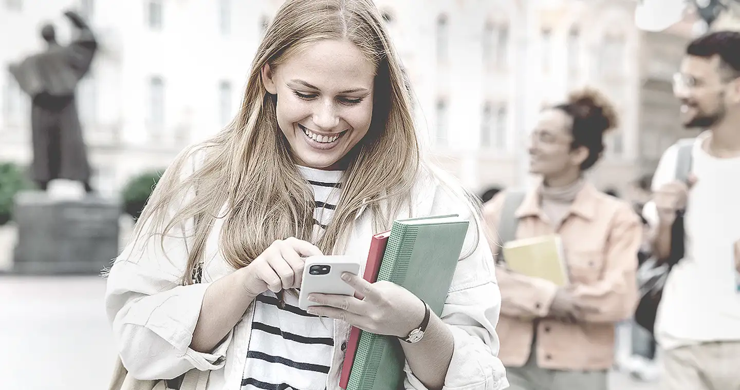 Eine junge Frau checkt am Smartphone ihre E-Mails und findet heraus, dass sie eine Zusage für ein Stipendium bekommen hat.