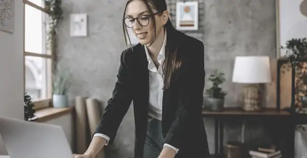 Eine Wirtschaftspsychologin arbeitet im Büro im Stehen am Laptop.