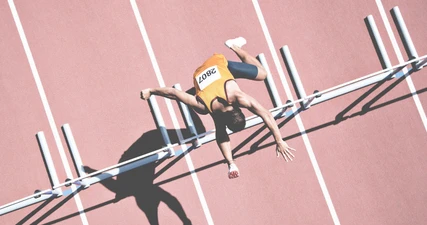 Sportlerin springt über Hürde.