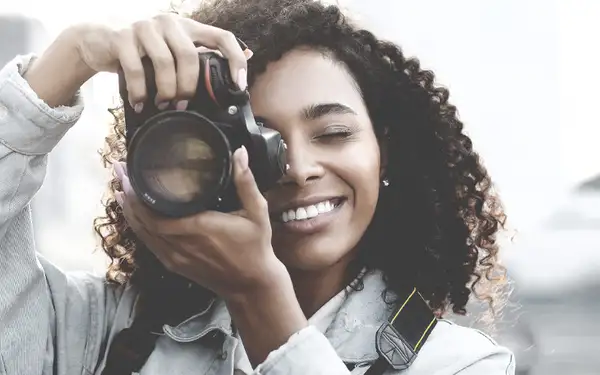 Eine junge Sportmarketing Studentin macht ein Foto mit ihrer Kamera