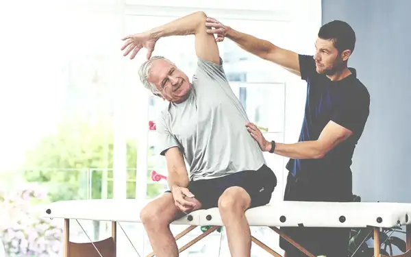 Junger Sporttherapeut behandelt einen älteren Patienten.