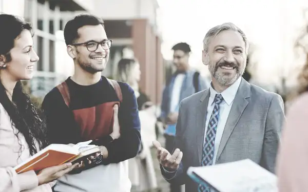 Drei Masterstudenten im Gespräch mit einem Professor. 