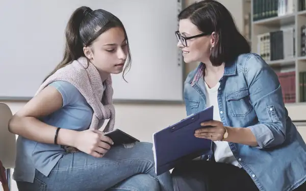 Eine Schulpsychologin spricht einfühlsam mit einer Schülerin und bietet ihr Unterstützung und Rat an.