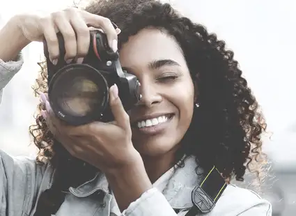 Eine junge Sportmarketing Studentin macht ein Foto mit ihrer Kamera