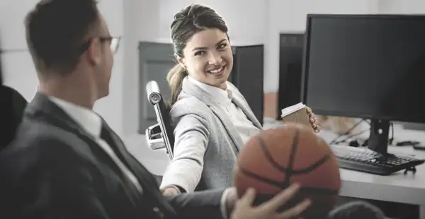 Sportmanager unterhält sich mit Kollegin im Büro.